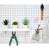 Three pots of succulents placed on a pegboard, along with a spray bottle, small shovel, and gardening tools.