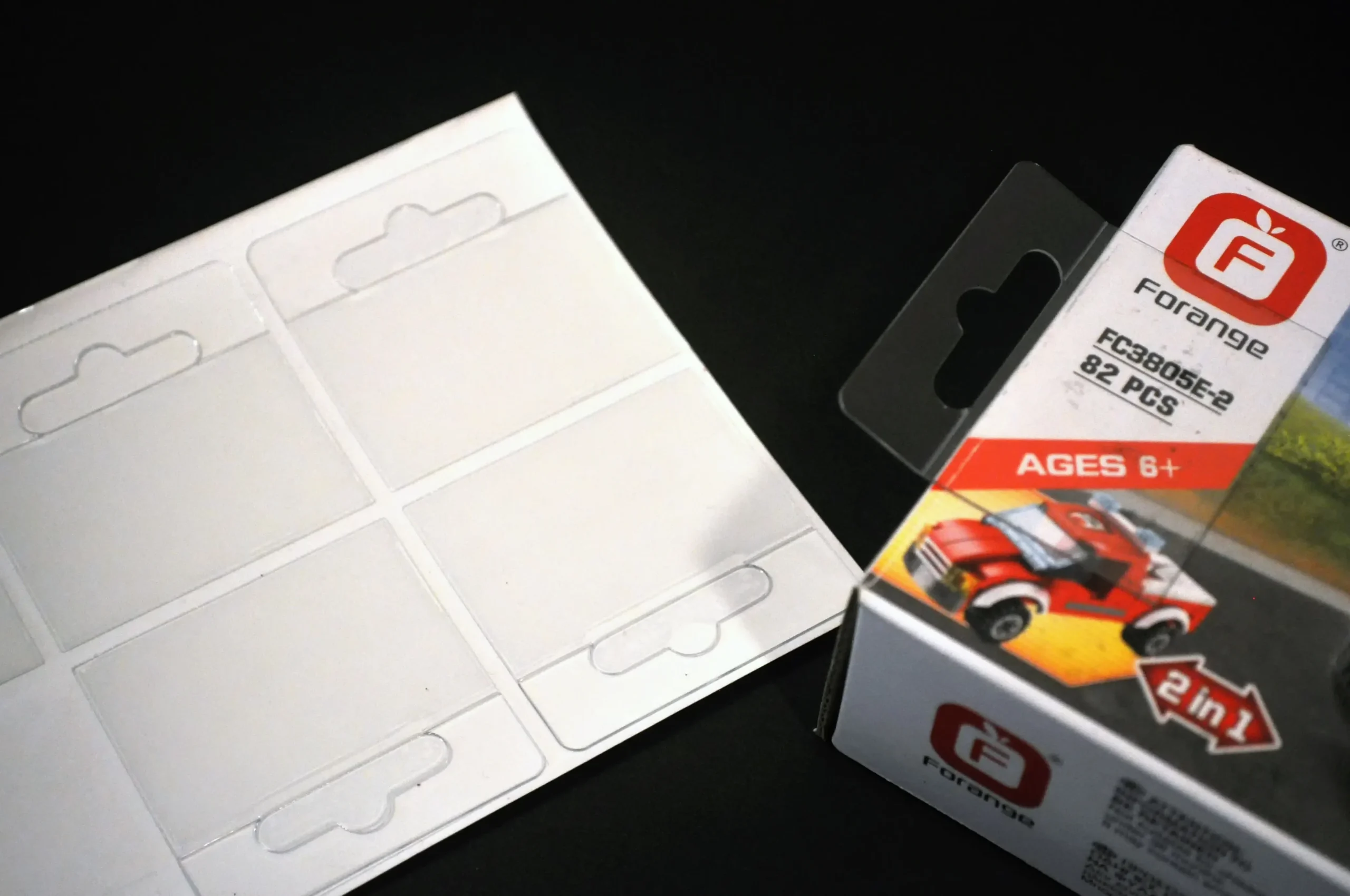 Transparent adhesive hang tabs on sheet (left) and applied on a product box (right) in a common Euro hole style for retail display.
