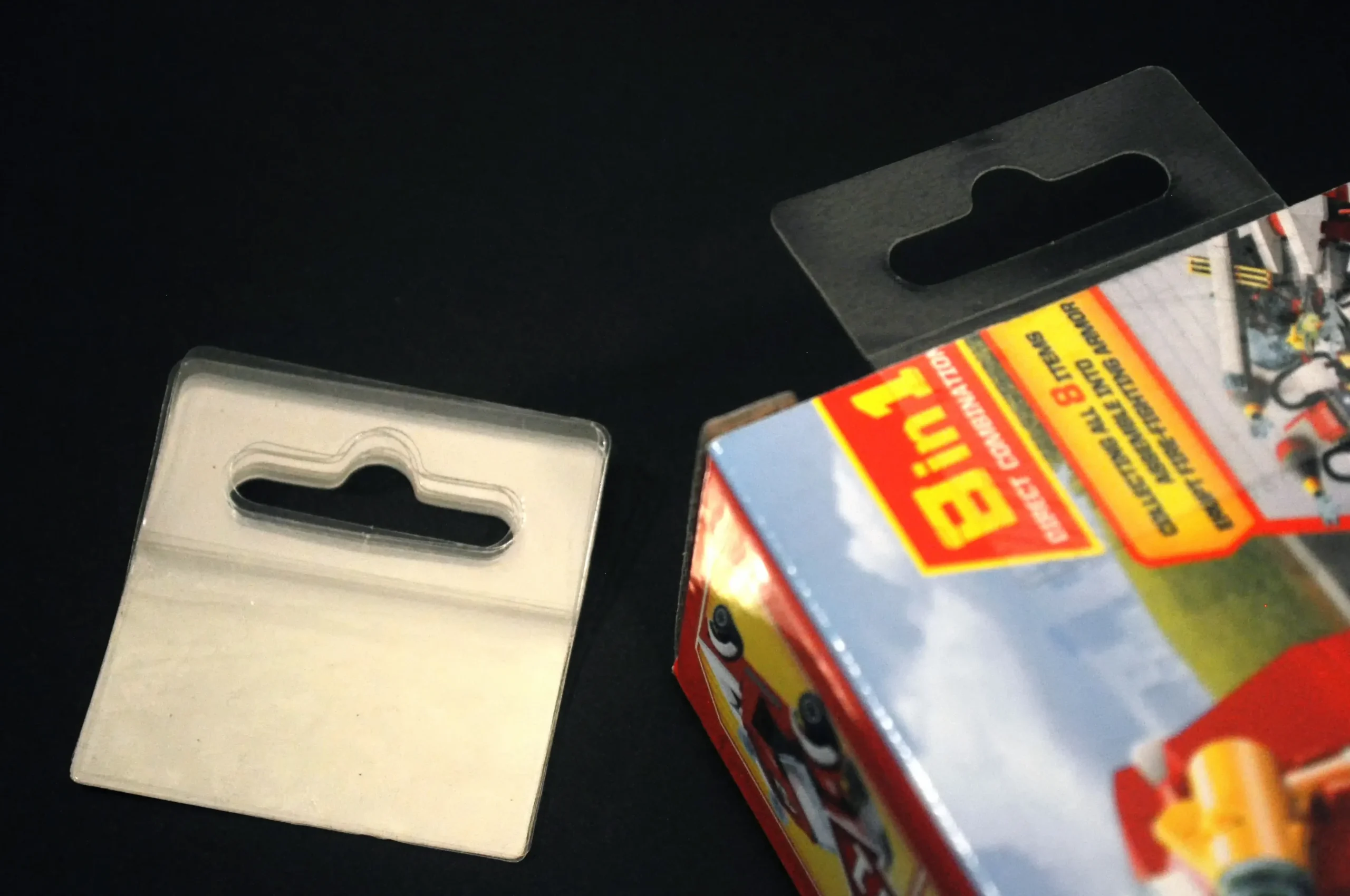 Clear self-adhesive hang tab with Euro hole, shown pad type and applied to a product box for hanging display.
