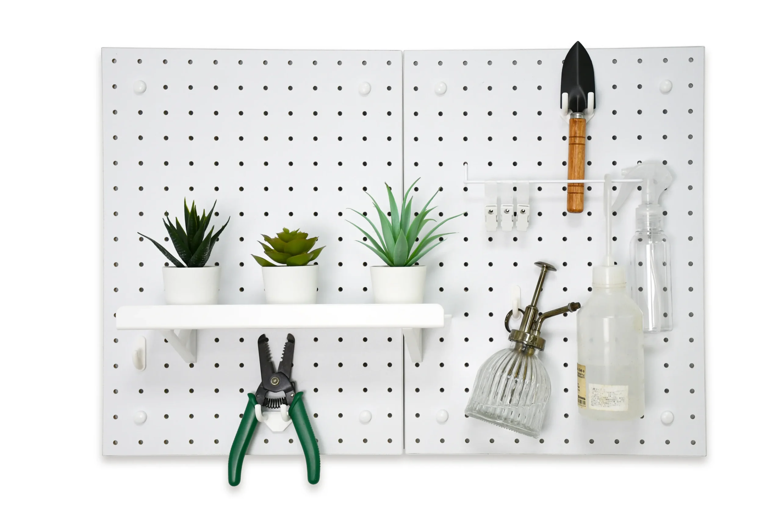 White pegboard wall organizer displaying gardening tools and three potted succulents. Features shears on the left, and a shovel with various spray bottles on the right, neatly arranged for practical storage.